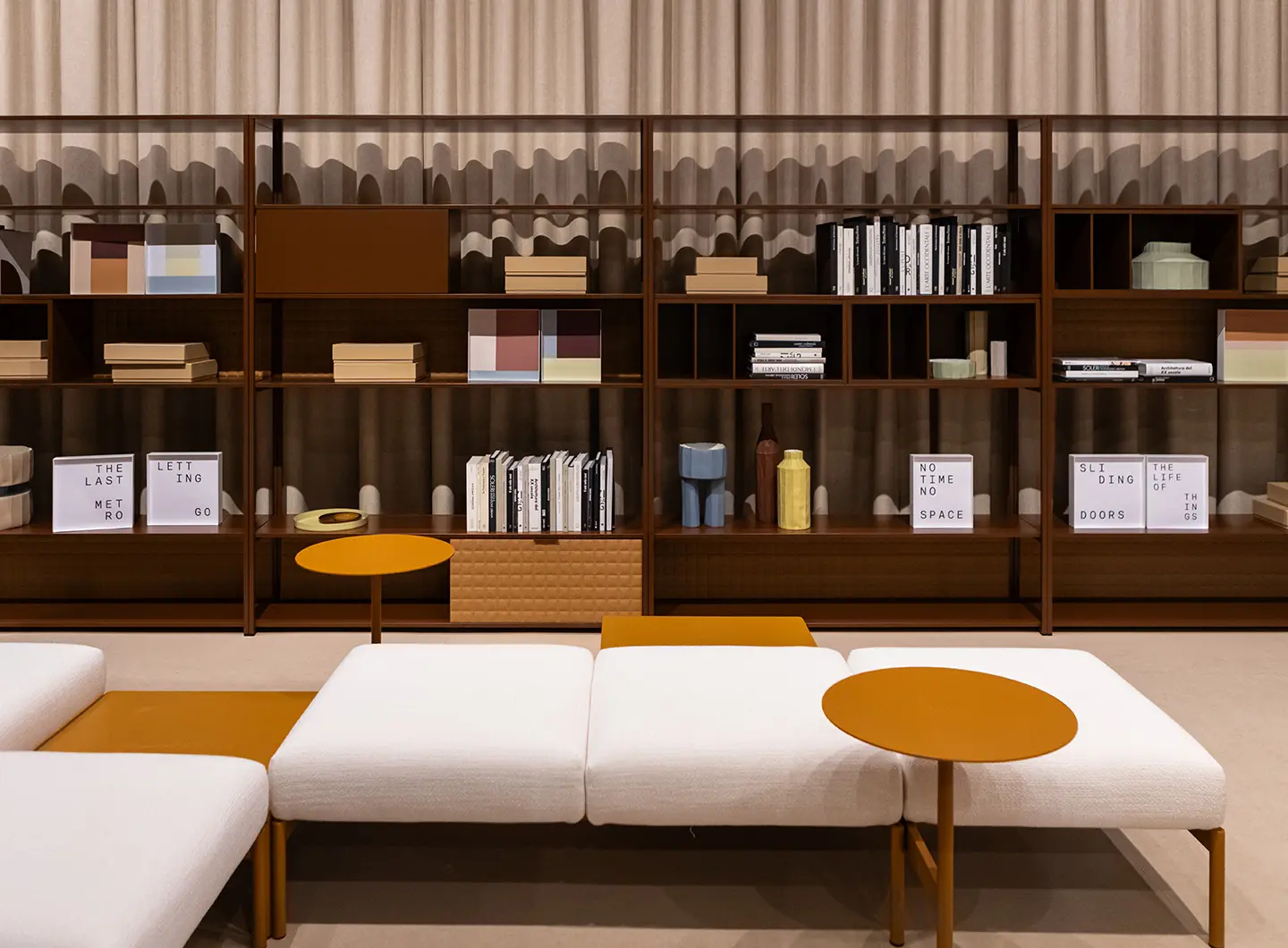 Brown freestanding bookcase and white chairs equipped with ochre metal shelves