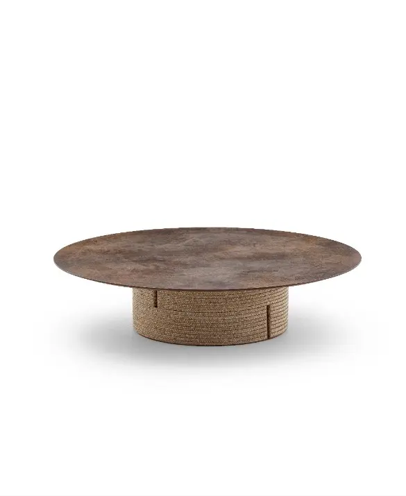 Tavolino basso rotondo da esterno della collezione Gianna di Varaschin, con base cilindrica avvolta in corda intrecciata chiara e piano circolare in finitura materica scura color ruggine, scontornato su fondo bianco.