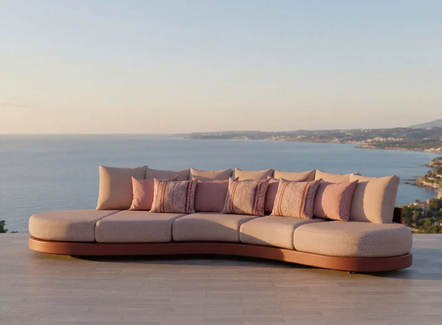 HARMONY Sofa by GANSK on a terrace with panoramic sea views, featuring a long curved base and plush cushions.