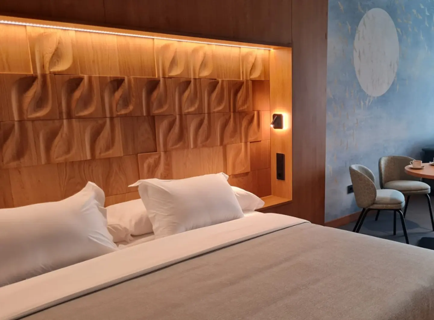 Luxury hotel room featuring a modern headboard with 3D oak wood panels in a Leaf pattern, integrated LED backlighting, and atmospheric wallpaper.