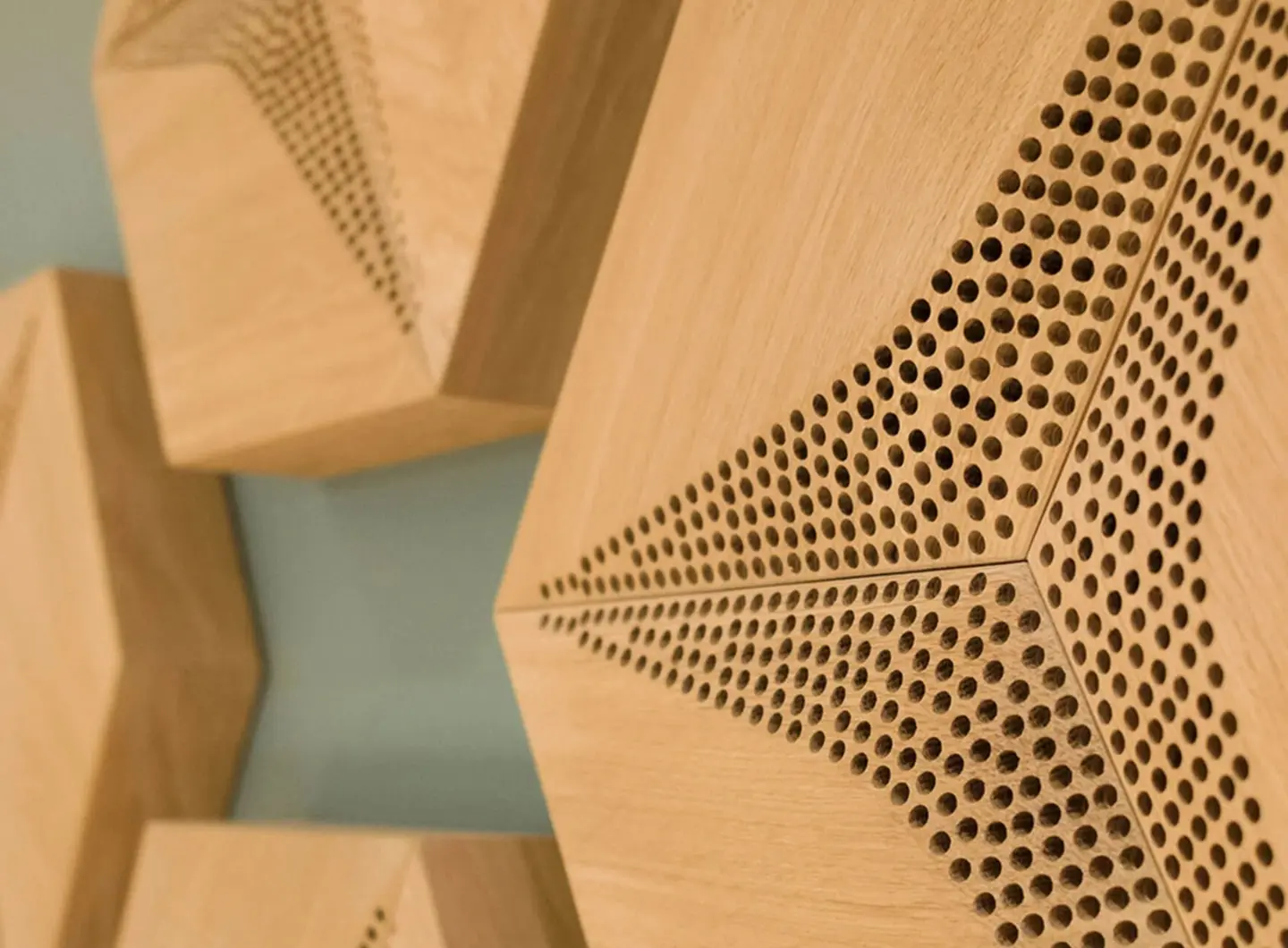 Close-up of 3D oak acoustic panels in Hexagon pattern, showcasing natural wood grain and precise sound-absorbing perforation holes.