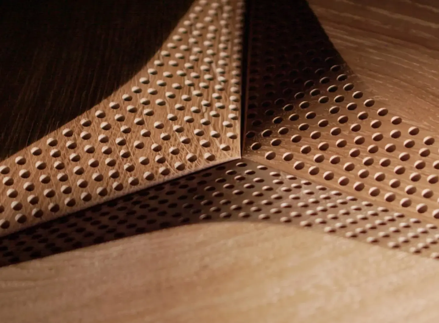 Macro close-up of the acoustic perforation system in a 3D oak Hexagon panel, showcasing precise holes and wood milling edges.