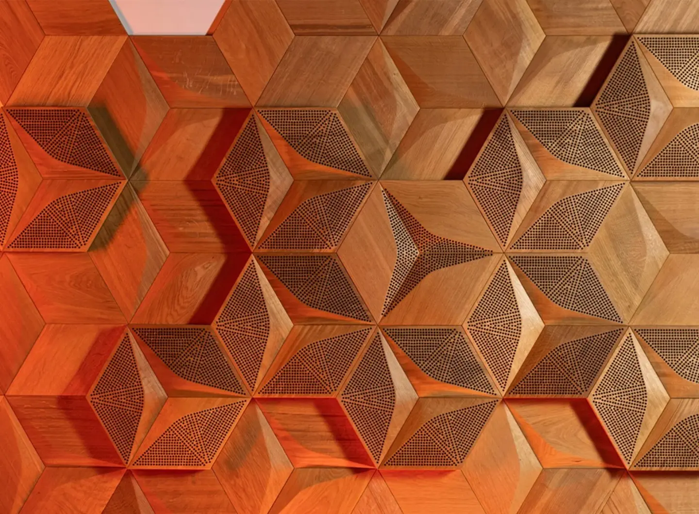 3D oak wall panels in Hexagon pattern with acoustic perforation, highlighted by warm ambient lighting, creating a deep dimensional shadow effect.