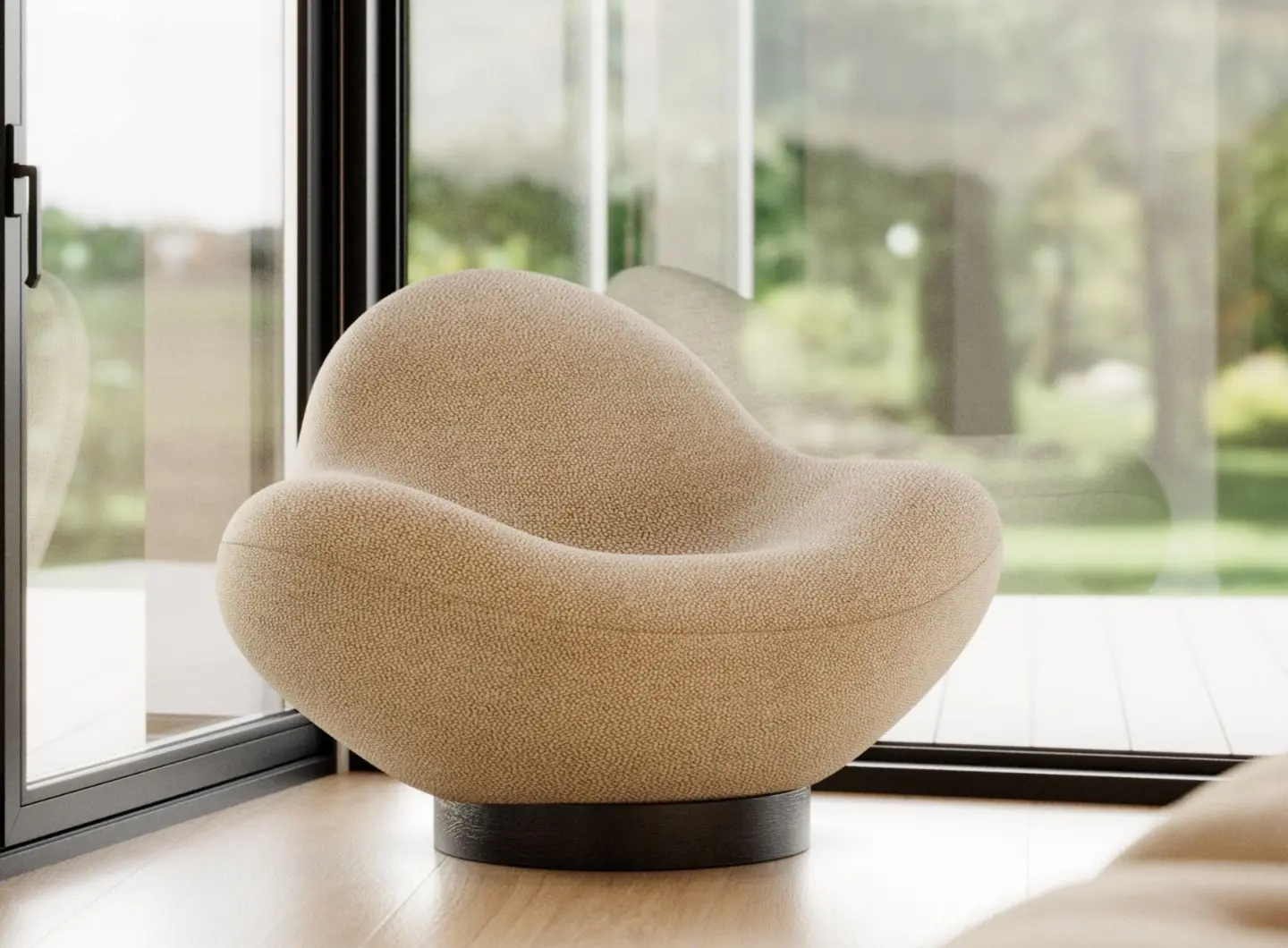 The Stone armchair, with its rounded, organic shapes and soft beige upholstery, is situated in a bright room with floor-to-ceiling windows overlooking lush greenery.