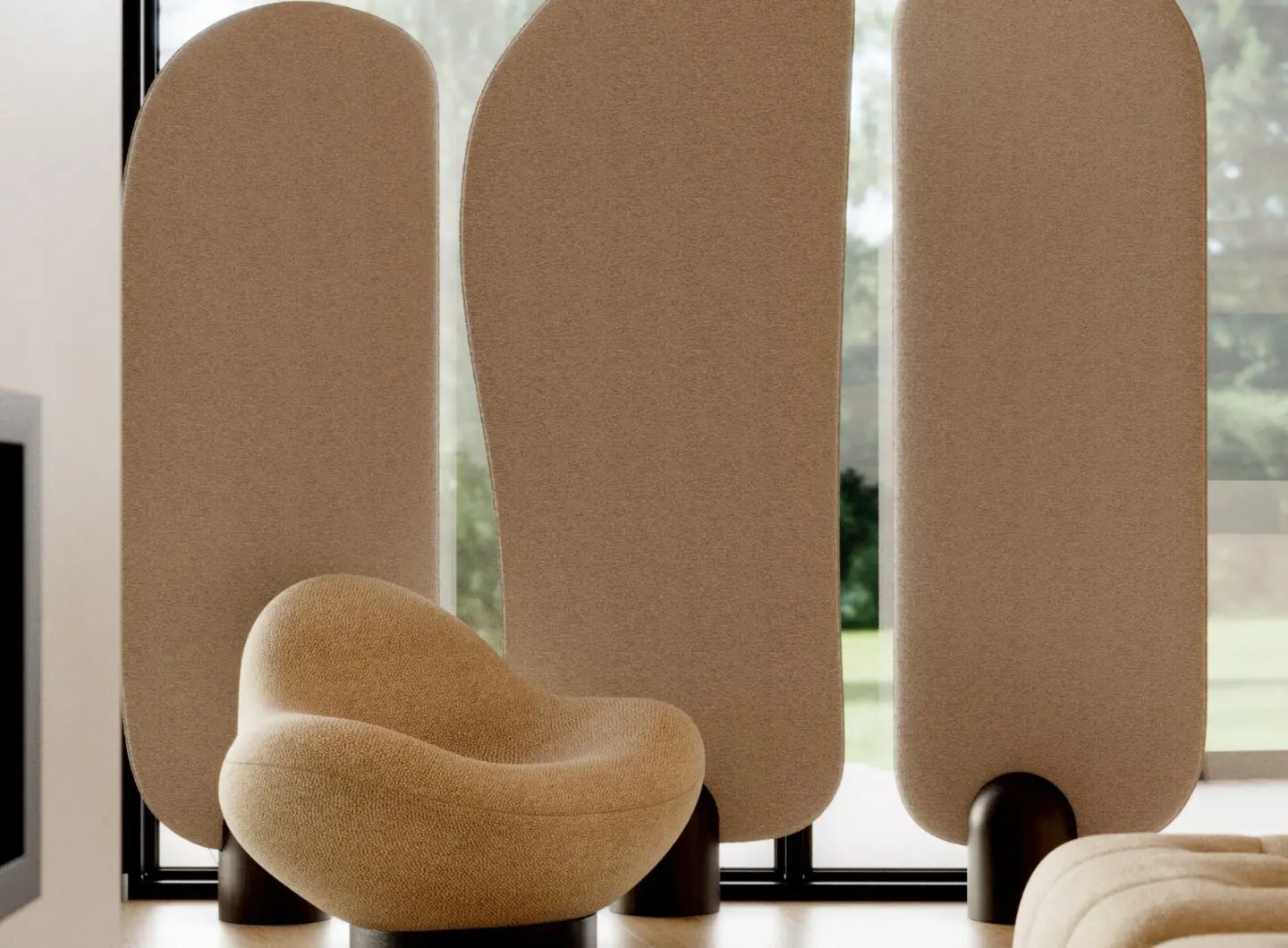 The Stone Screen stands behind a rounded beige lounge chair, composed of three tall curved panels in a soft neutral tone, each supported by dark rounded bases, in a bright interior with large windows and greenery outside.