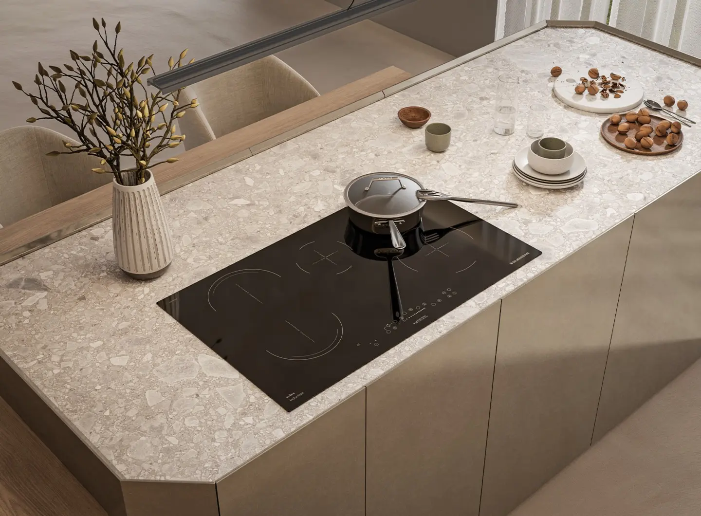 Top-down shot of a large kitchen island featuring a 90 cm black glass induction hob with 5 zones, including one bridge zone and touch controls. The surface is styled with plates, ceramic bowls and a stainless steel pot, creating a convivial and refined atmosphere.