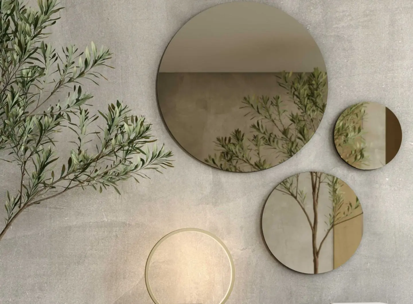 The Circle Mirror appears as part of a composition of round mirrors in varying sizes mounted on a textured grey wall, softly reflecting branches and warm light to create a serene, harmonious focal point within the space.