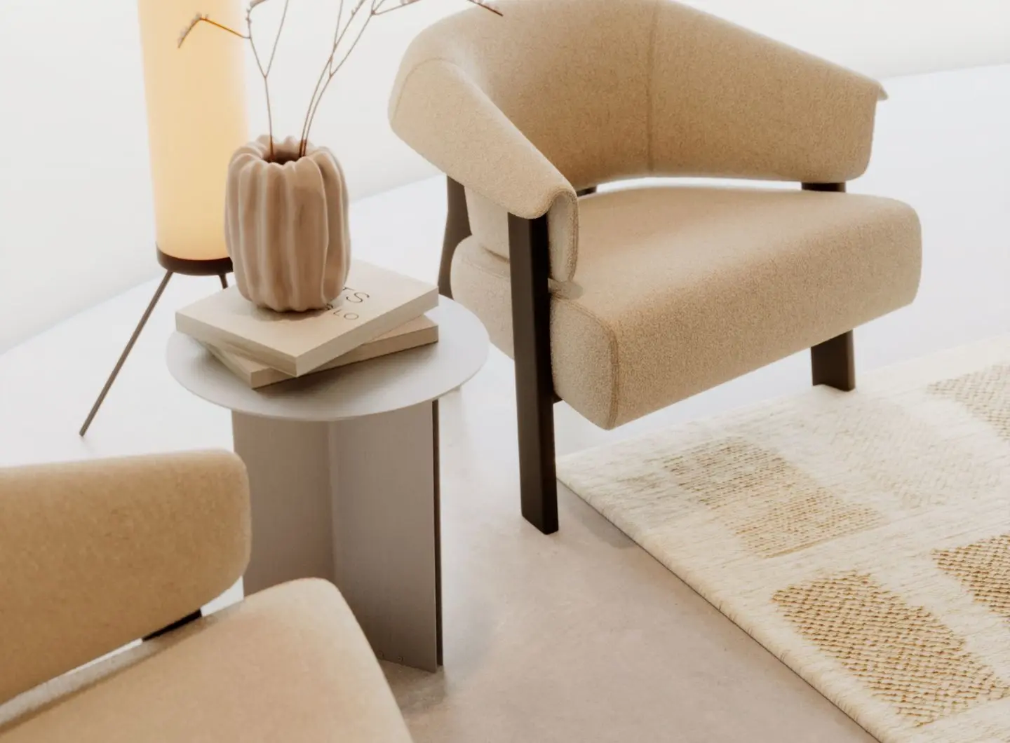 The Steel Side Table is shown between two beige armchairs as a round steel table with a light grey top and vertical panel base, holding stacked books and a sculptural vase beneath a warm floor lamp, adding a calm, refined touch to the minimalist seating nook.