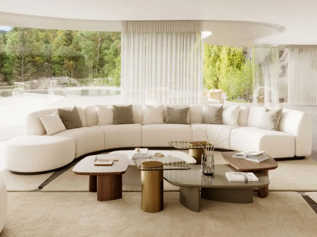 The Dolomites Coffee Table appears as a set of three contemporary tables in front of a curved beige sofa, featuring mixed materials including wood, brass, and a glossy grey surface, arranged at varying heights and shapes to create a dynamic centerpiece within a bright living room overlooking greenery.