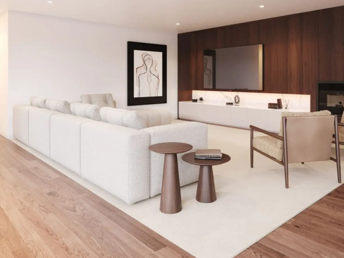 The Antónia Sofa appears as a white bouclé modular sectional arranged in a minimalist living room beside two round wooden side tables, a beige wooden‑framed armchair, and a cream rug, set against a built‑in media wall with cabinetry, dark wood paneling, and abstract line art.