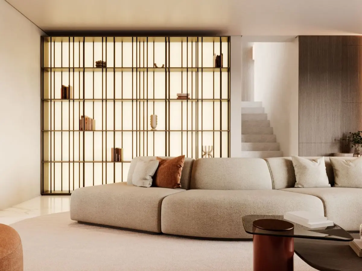 The Buren Bookcase appears as a backlit shelving installation with slender vertical frames and warm lighting, placed behind a curved beige sofa and styled with a few decorative objects, becoming an architectural focal point that brings order and quiet elegance to the room.