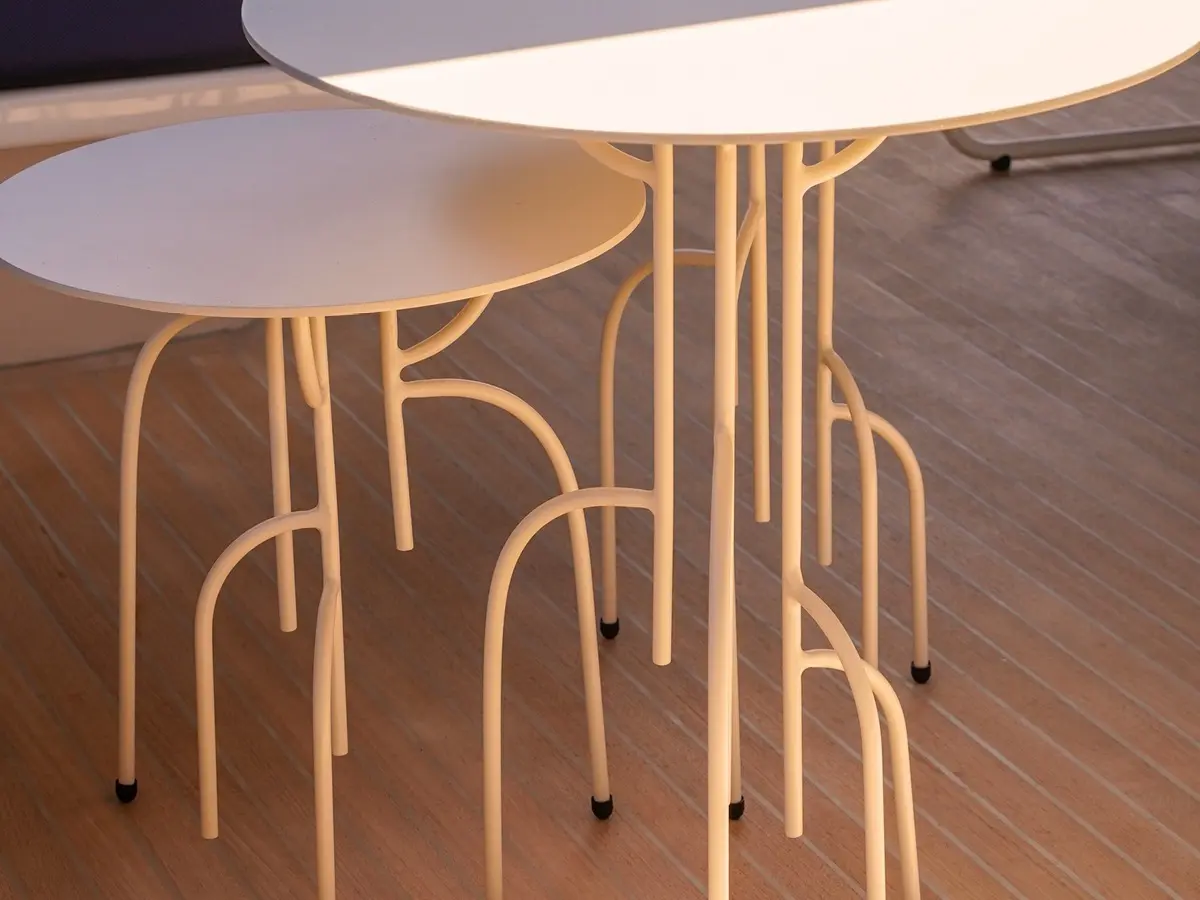 White coffee tables at two different heights. The legs are slender and branch out like roots.