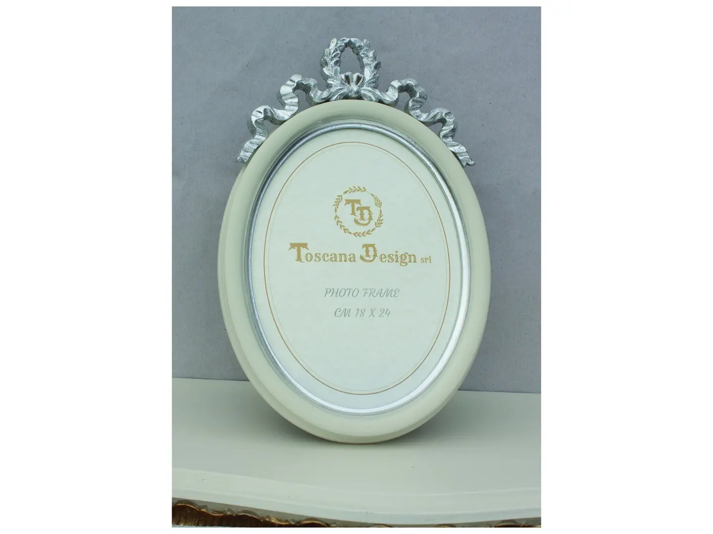 This oval photo frame is made of solid wood, sturdy and pleasant to the touch. The smooth surface is finished in ivory, with a bright silver leaf trim and top edge. The rounded shape and delicate details make it elegant and suitable for a variety of settings.