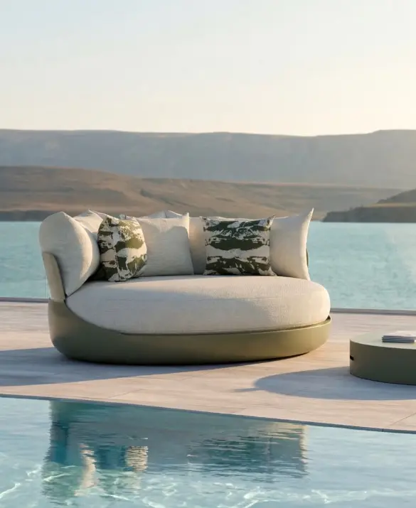 HARMONY Day Bed by GANSK on a poolside terrace overlooking the sea, paired with a low round coffee table and layered cushions