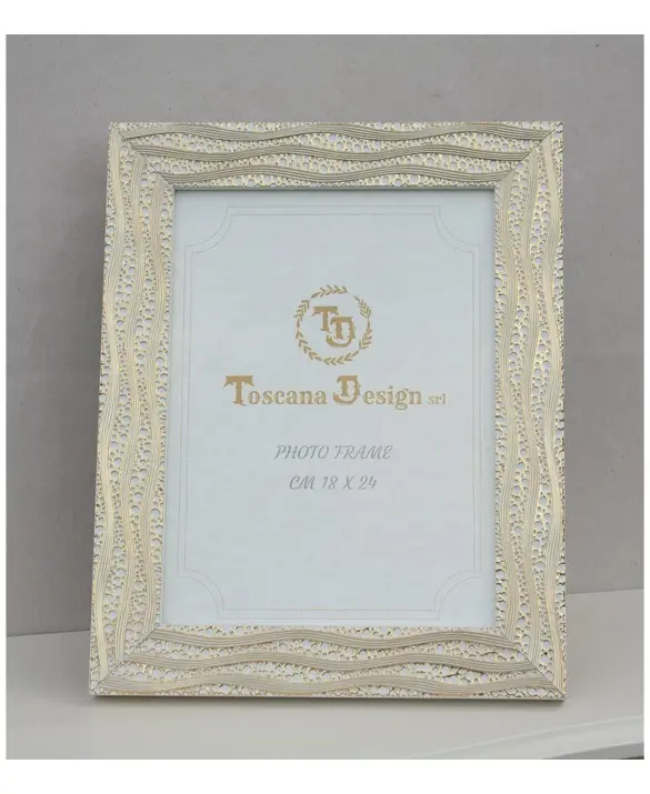 Elegant, classic-style photo frame in ivory. It features a rectangular shape with edges decorated with delicate, harmonious gold motifs. The surface has a subtle texture reminiscent of handcrafted workmanship. Suitable for 18x24 cm photographs. Ideal for refined settings, it lends a bright, sophisticated look to spaces.