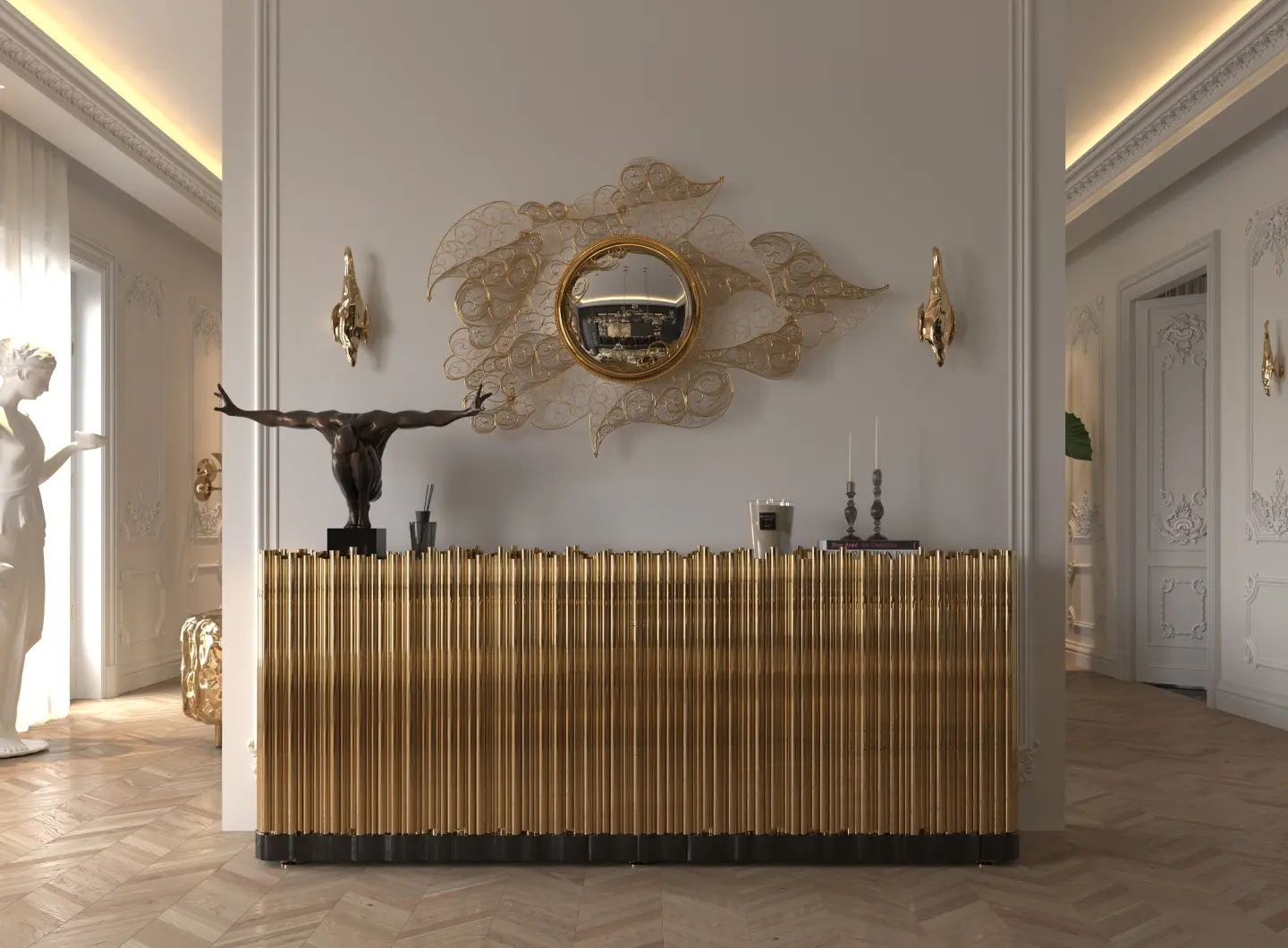 A luxurious classical-modern hallway. At the center is the Symphony Sideboard, a gold-finished credenza with a distinctive vertical pipe texture and a dark base. Above it hangs the Filigree Mirror, a round mirror with a gold frame and a large, intricate gold wire-sculpture filigree art piece on the wall. The sideboard displays a bronze sculpture and candlesticks. The setting features ornate white wall moldings, a herringbone-patterned wood floor, gold sconces, and a classical white sculpture to the left.
