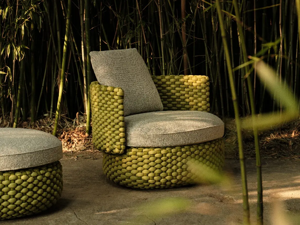 Oleia swivel lounge armchair and Pouf in an outdoor setting.