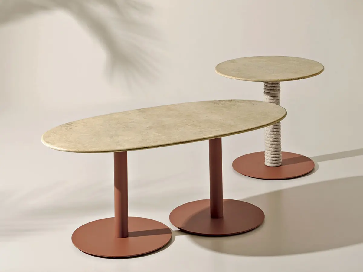 On the left, Noon table with oval travertine top and caramel base. On the right, Noon table with round travertine top and natural rope base.