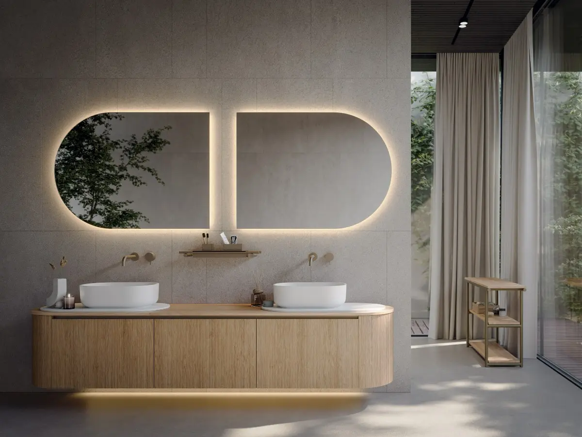 Bathroom Novello. Base units with “Elle” door and Rovere Naturale wood top, Titanium finish aluminum handle. Rounded side unit with pull-out drawer or with door and shelf . Oblon washbasin and tray in matte white Teknorit. Backlit mirror.