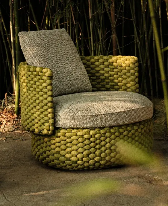 Oleia swivel armchair in Fine Grass rope, immersed in greenery.