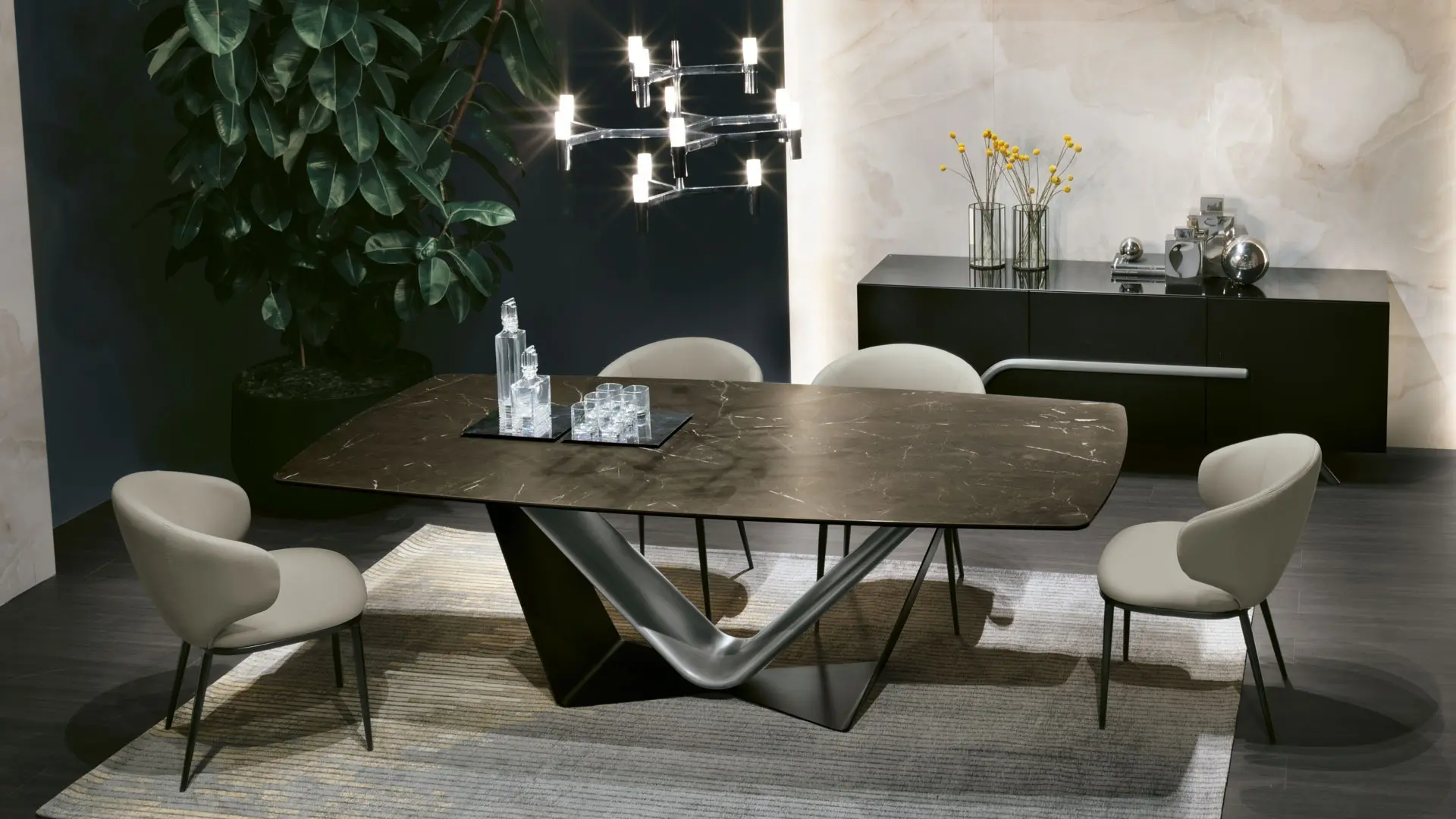 Tavolo VELAR con piano in gres effetto marmo scuro e base scultorea in metallo, abbinato a sedie CANDY imbottite e madia DILECTA in un elegante living contemporaneo.