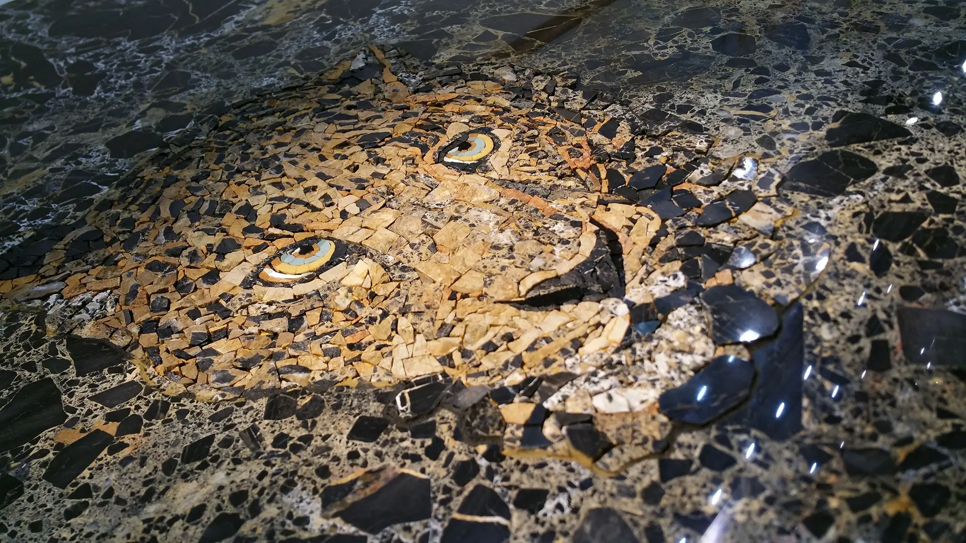 Mosaico realizzato a mano raffigurante un leopardo inserito in una lastra di marmo portoro